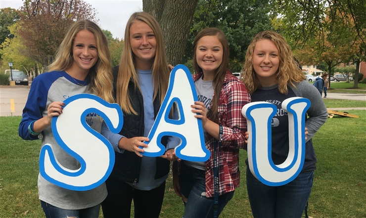 Photo of students holding letters: S A U