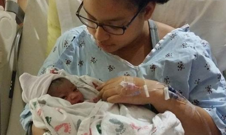 Reina holding her newborn daughter in 2014