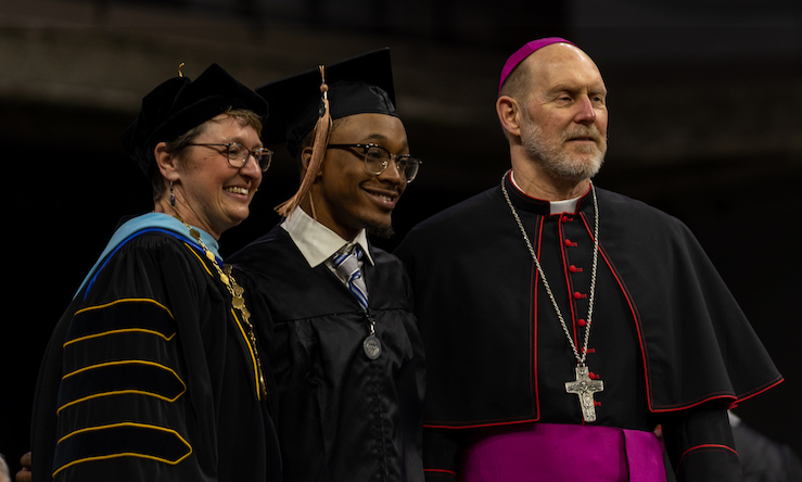 President amy and bishop with graduate