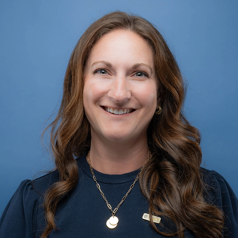 Bre Thompson smiles into the camera against a blue background.