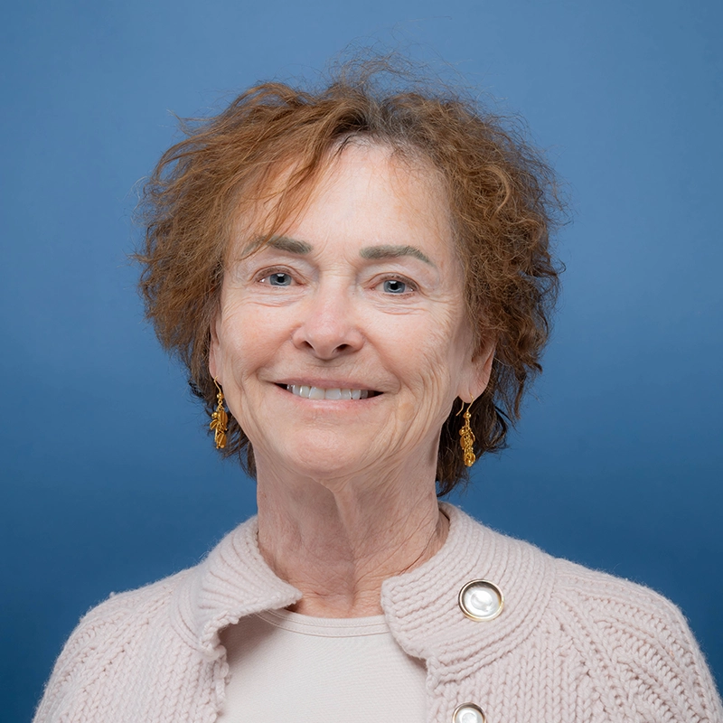 Dyan Smith smiles into the camera against a blue background.