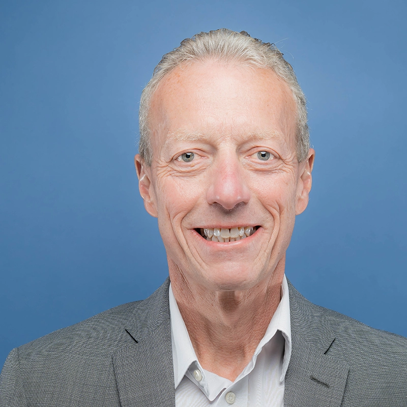 Jerry Lyphout smiles into the camera against a blue background.