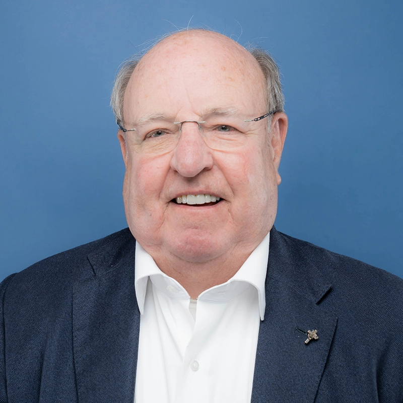 Ken Brune smiles into the camera against a blue background.