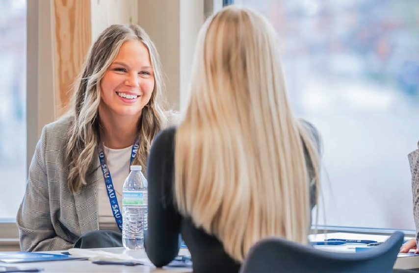 A student looking and smiling at another student