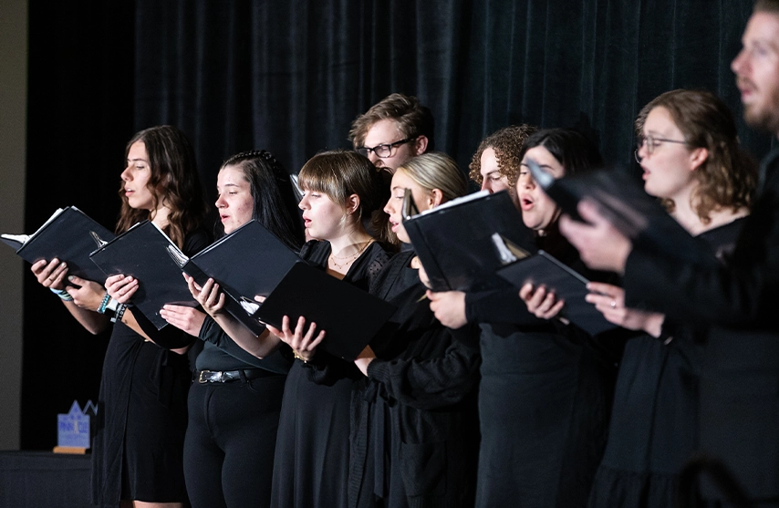 A group of choir members dressed in black singing together.