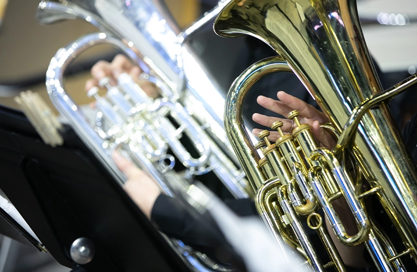 A close-up shot of two musicians playing the euphonium in the brass section.