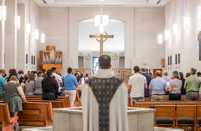 People stand with their backs to the camera as they pray during Mass.