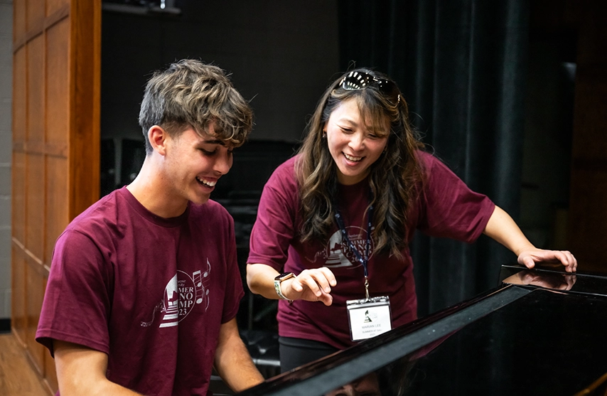 A St. Ambrose University instructor guides a student in playing the piano during the St. Ambrose University Piano camp.