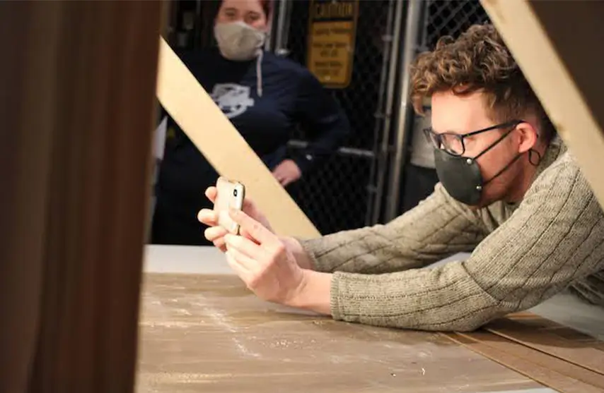 A man leaning over and taking a picture with his phone.