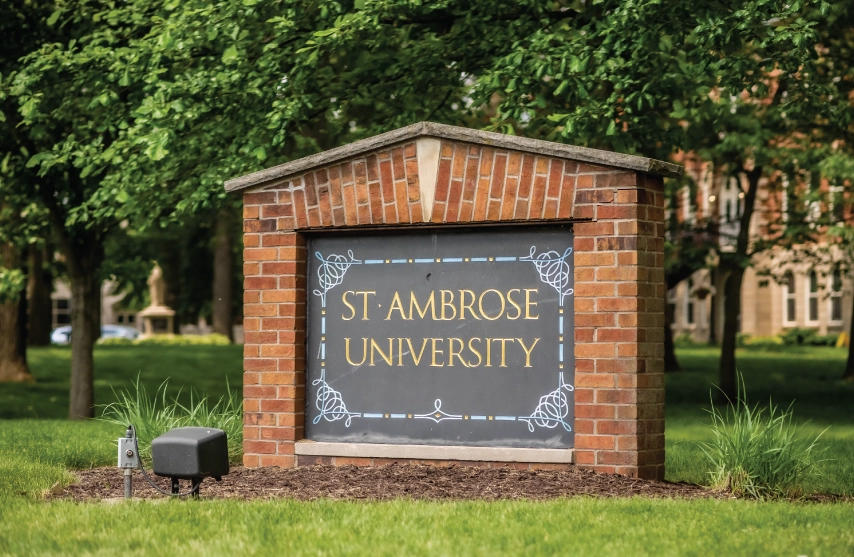 A sign that says St. Ambrose University outside in front of trees.