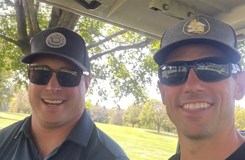 Two men smiling for a selfie outside.