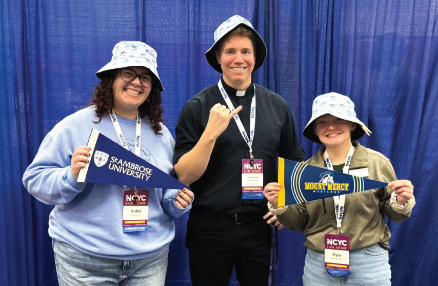 Three individuals smiling in bucket hats, with pennant flags for SAU and MMU.