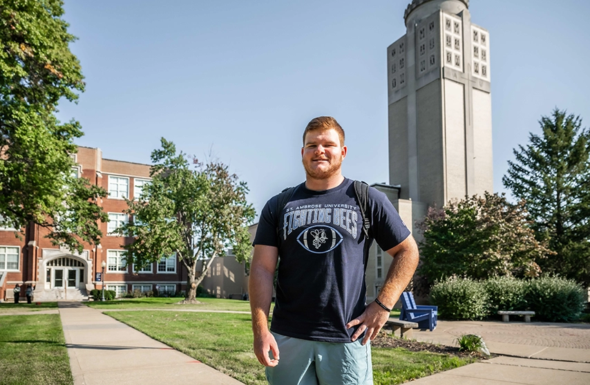 Kaeden Hutchens stands in front of academic buildings on St. Ambrose University.