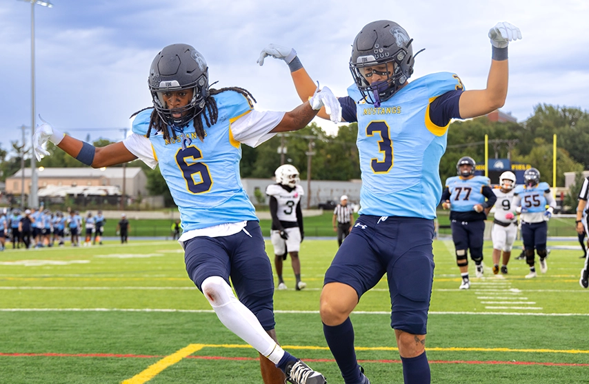 Two Mount Mercy football players celebrating in the endzone.