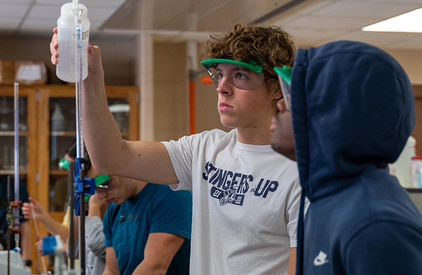Students wear protective gear as they work in a chemistry lab.