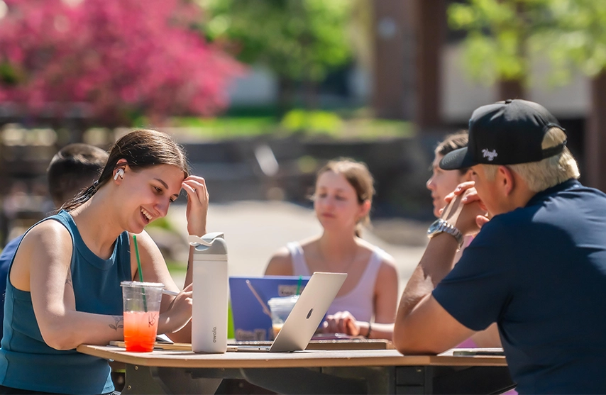 A group of students smile while studying outside on the SAU campus.