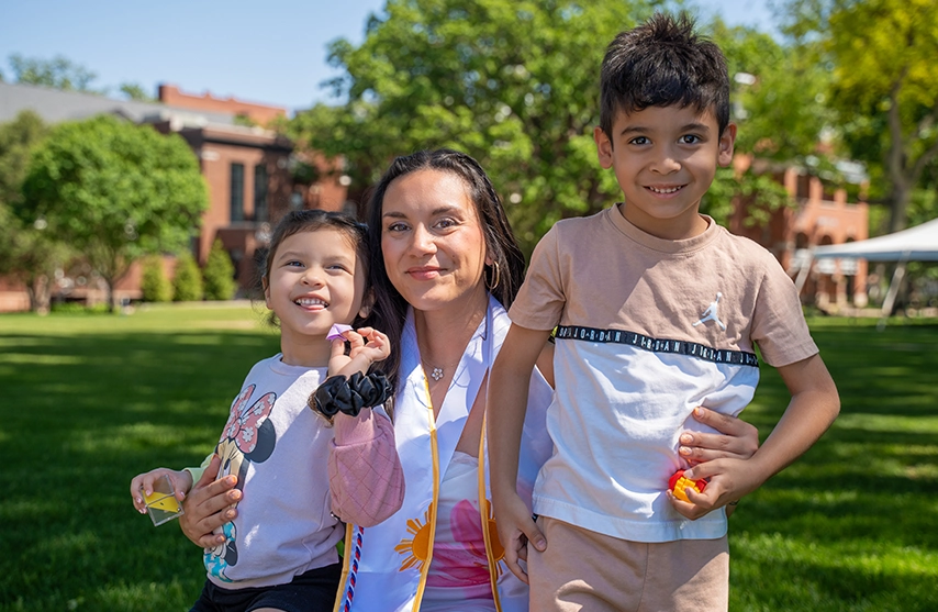 Nursing student Sydnee Cosner '26 poses on the SAU lawn with two of her children.