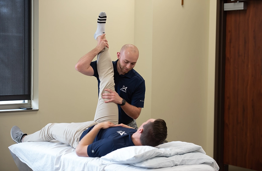 A student practices phyiscal therapy skills on a fellow student.