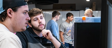 Students work together at a computer, testing electronics connected to a desktop workstation