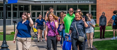 A student tour guide leads a group of students and families past the Wellness and Recreation Center at St. Ambrose University.