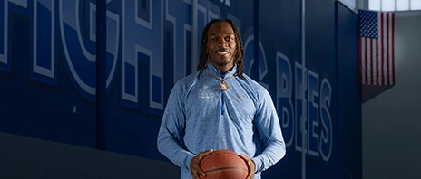 Jaylen Brazzle standing in a gymnasium holding a basketball.
