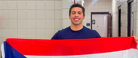 Khalil Ruiz smiles into the camera as he holds up the Puerto Rican flag.