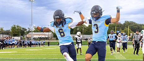 Two Mount Mercy football players celebrating in the endzone.