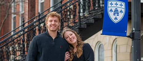 Jaxson Eisenbarth ‘27 walked Ellie Seberger ‘26 stand together and smile at the camera on the St. Ambrose University campus.