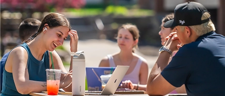 A group of students smile while studying outside on the SAU campus.