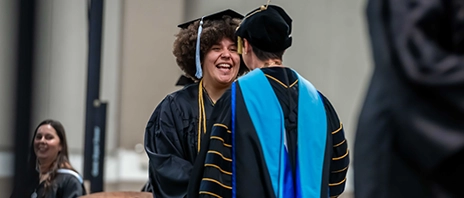A student smiles as she receives her degree from St. Ambrose University.