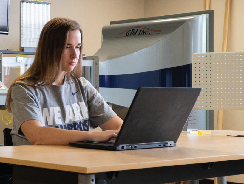 Female student working on a laptop in an engineering lab